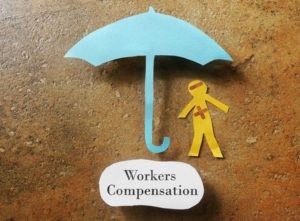 42311858 - bandaged paper man under umbrella with workers compensation note below
